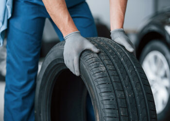 One more improvement and job will be done. Mechanic holding a tire at the repair garage. Replacement of winter and summer tires.