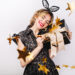 Crazy party time of beautiful women in elegant black dress with gift box celebrating birthday,sparkling gold confetti, having fun, dancing. Emotion face,red lips, eyes closed.